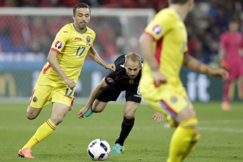 Albania's Migjen Basha, center, looks the ball as Romania's Lucian Sanmartean, left, goes for the ball during the Euro 2016 Group A soccer match between Romania and Albania at the Grand Stade in Decines-­Charpieu, near Lyon, France, Sunday, June 19, 2016. (AP Photo/Pavel Golovkin)