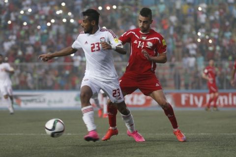 UAE's Mohamed Gharib, left, tries to avoid Palestinian Abdallah Jaber during their World Cup soccer qualifying match at the Faisal al-Husseini stadium in the West Bank town of Al-Ram, north of Jerusalem, Tuesday, Sept. 8, 2015. (AP Photo/Majdi Mohammed)