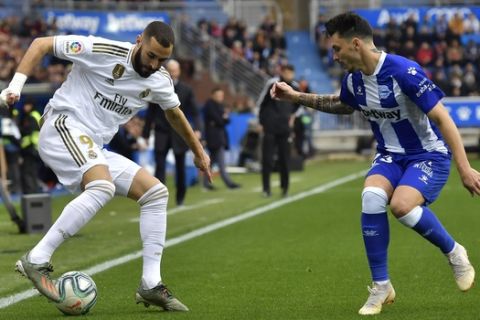 Real Madrid's Karim Benzema, left, duels for the ball with Alaves' Ximo Navarro during the Spanish La Liga soccer match between Real Madrid and Alaves at Mendizorroza stadium, in Vitoria, northern Spain, Saturday, Nov. 30, 2019. (AP Photo/Alvaro Barrientos)