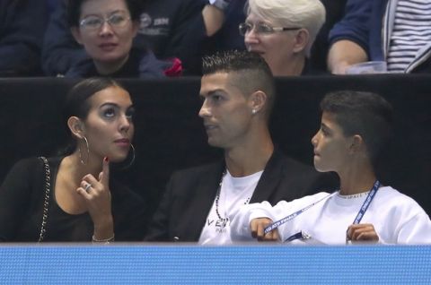 Cristiano Ronaldo, center, with his partner Georgina Rodriguez, and his son Cristiano Ronaldo Junior watches as Novak Djokovic of Serbia plays John Isner of the United States in their ATP World Tour Finals singles tennis match at the O2 Arena in London, Monday Nov. 12, 2018. (Adam Davy/PA via AP)