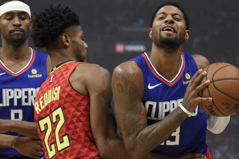 Los Angeles Clippers forward Paul George, right, moves the ball while Atlanta Hawks forward Cam Reddish defends during the first half of an NBA basketball game in Los Angeles, Saturday, Nov. 16, 2019. (AP Photo/Kelvin Kuo)