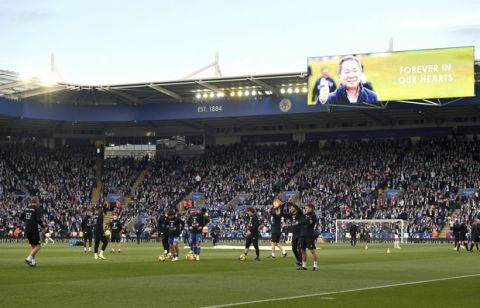 Tributes to those who lost their lives in the Leicester City helicopter crash including Leicester City Chairman Vichai Srivaddhanaprabha on the screens as Leicester City players warm up ahead of the English Premier League soccer match at the King Power Stadium, Leicester, England. Saturday Nov. 10, 2018. (Joe Giddens/PA via AP)