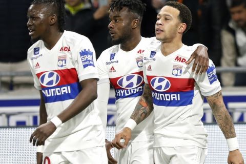 Lyon's Memphis Depay, right, celebrates with his teammates Maxwel Cornet, center, and Bertrand Traore, after he scored a goal against Toulouse during their French League One soccer match in Decines, near Lyon, central France, Sunday, April 1, 2018. (AP Photo/Laurent Cipriani)