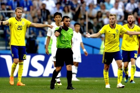 Swedish players ask referee Joel Aguilar from El Salvador to review a decision during the group F match between Sweden and South Korea at the 2018 soccer World Cup in the Nizhny Novgorod stadium in Nizhny Novgorod, Russia, Monday, June 18, 2018. the review resulted in a penalty for Sweden from which they scored the opening goal. (AP Photo/Petr David Josek)