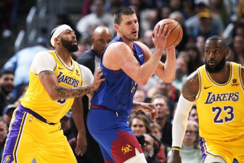 Denver Nuggets center Nikola Jokic, center, looks to pass the ball as Los Angeles Lakers forward Anthony Davis, left, and forward LeBron James defend during the first half of an NBA basketball game Tuesday, Oct. 24, 2023, in Denver. (AP Photo/David Zalubowski)