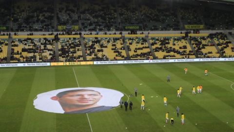 Nantes players warm up next to a giant canvas showing late Argentinian player Emiliano Sala is pictured in La Beaujoire stadium prior the French League One soccer match between Nantes against Bordeaux in Nantes, western France, Sunday, Jan. 26, 2020. Nantes paid an emotional tribute to Emiliano Sala by wearing a special blue and white (AP Photo/Michel Euler)