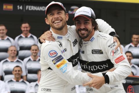 McLaren driver's Jenson Button, left, of Britain and Fernando Alonso of Spain joke as they pose for a photo with their team in front of their pit lane garage ahead of the first practice session for the Japanese Formula One Grand Prix at the Suzuka International Circuit in Suzuka, Japan, Friday, Oct. 7, 2016. (AP Photo/Eugene Hoshiko)