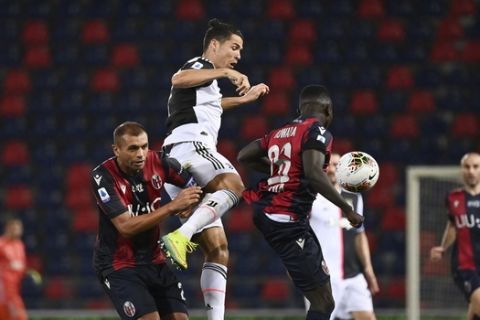 Juventus' Cristiano Ronaldo jumps for the ball against Bologna's Danilo and Musa Juwara during the Serie A soccer match between Bologna FC and Juventus FC at Stadio Renato Dall'Ara stadium in Bologna, Monday June 22, 2020. (Massimo Paolone/LaPresse via AP)