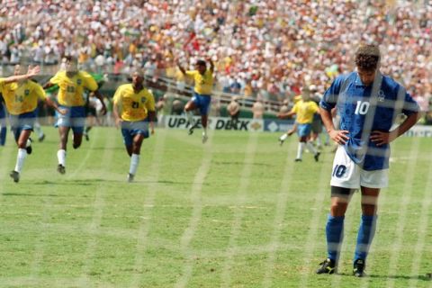 LOS ANGELES, UNITED STATES:  Brazilian players run to join their teammates as Italian midfielder Roberto Baggio bows his head after he missed his penalty kick giving Brazil a 3-2 victory in the shoot-out session (0-0 after extra time) at the end of the World Cup final, 17 July 1994 at the Rose Bowl in Pasadena. Brazil won its fourth World Cup title after 1958, 1962 and 1970.   AFP PHOTO/OMAR TORRES (Photo credit should read OMAR TORRES/AFP/Getty Images)