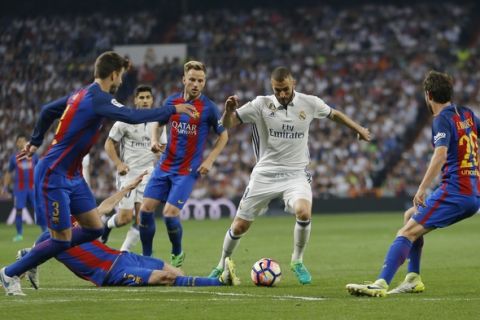 Real Madrid's Karim Benzema, center, tries to dribble pas Barcelona's Gerard Pique, left, Sergio Busquets, and Sergi Roberto, during a Spanish La Liga soccer match between Real Madrid and Barcelona, dubbed 'el clasico', at the Santiago Bernabeu stadium in Madrid, Spain, Sunday, April 23, 2017. (AP Photo/Francisco Seco)