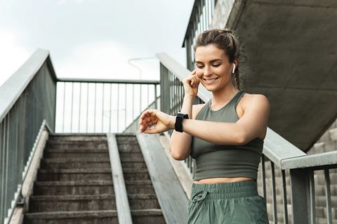 Young athletic woman using smartwatch during her fitness workout on city street