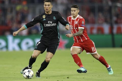 Real Madrid's Cristiano Ronaldo, left, and Bayern's James challenge for the ball during the semifinal first leg soccer match between FC Bayern Munich and Real Madrid at the Allianz Arena stadium in Munich, Germany, Wednesday, April 25, 2018. (AP Photo/Matthias Schrader)