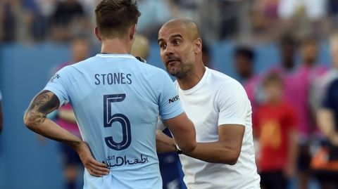 Manchester City head coach Pep Guardiola talks with defender John Stones (5) during the second half of an International Champions Cup soccer match against Tottenham Saturday, July 29, 2017, in Nashville, Tenn. Manchester City won 3-0. (AP Photo/Mark Zaleski)