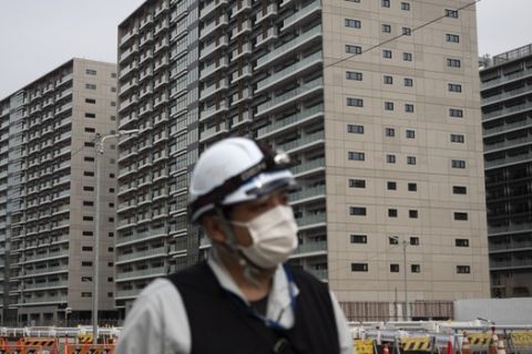 A worker walks through the athletes' village for the Tokyo 2020 Olympics, in Tokyo, Monday, March 23, 2020. The IOC will take up to four weeks to consider postponing the Tokyo Olympics amid mounting criticism of its handling of the coronavirus crisis that now includes Canada saying it won't send a team to the games this year and the leader of track and field, the biggest sport at the games, also calling for a delay. \(AP Photo/Jae C. Hong)