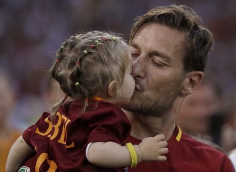Roma's Francesco Totti kisses her daughter Isabel as he salutes his fans after an Italian Serie A soccer match between Roma and Genoa at the Olympic stadium in Rome, Sunday, May 28, 2017. Francesco Totti is playing his final match with Roma against Genoa after a 25-season career with his hometown club. (AP Photo/Alessandra Tarantino)