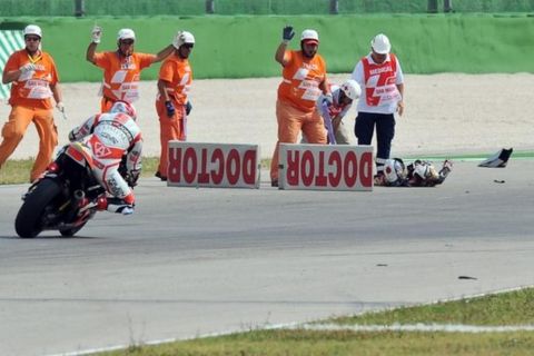 Officials stand next to Japanese rider Shoya Tomizawa of Technomag-CIP team (C) after he was propelled over 40 metres and off the track into the gravel during the Italian Moto2 motorcycling race at Santa Monica, Misano Adriatico track on September 5, 2010. Tomizawa died from injuries sustained in a crash in the San Marino Moto2 Grand Prix. The 19-year-old Technomag-CIP rider came off his Suter bike when under pressure from the fast charging Italian Alex de Angelis. AFP PHOTO / ANDREAS SOLARO (Photo credit should read ANDREAS SOLARO/AFP/Getty Images)
