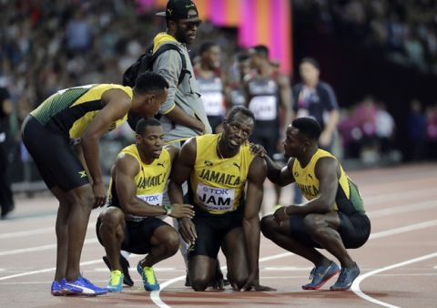 Jamaica's Usain Bolt, second right, is assisted by his teammates after he pulled up injured in the final of the Men's 4x100m relay during the World Athletics Championships in London Saturday, Aug. 12, 2017. (AP Photo/David J. Phillip)