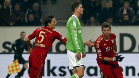 Bayern's Mario Mandzukic of Croatia, right celebrates his side's opening goal with his teammate Daniel van Byten, left, during the German first division Bundesliga soccer match between VfL Wolfsburg and FC Bayern Munich in Wolfsburg, Germany, Friday, Feb. 15, 2013. In the center is Wolfsburg's Alexander Madlung. (AP Photo/Michael Sohn) 