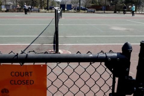 A few people play tennis despite the court being closed at Cartwright Park in Evanston, Ill., Wednesday, March 25, 2020. Local parks closed playgrounds and courts in response to coronavirus pandemic. (AP Photo/Nam Y. Huh)