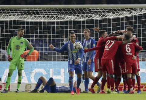 Hertha goalkeeper Rune Jarstein, left, reacts as Bayern's Kingsley Coman and his teammates, right, celebrate their side's 3rd goal during a German Soccer Cup round of sixteen match between Hertha BSC Berlin and FC Bayern Munich in Berlin, Germany, Wednesday, Feb. 6, 2019. (AP Photo/Michael Sohn)