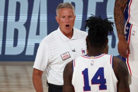 Philadelphia 76ers head coach Brett Brown, left, talks with forward Norvel Pelle (14) during a timeout in an NBA basketball game against the Houston Rockets, Friday, Aug. 14, 2020, in Lake Buena Vista, Fla. (Kim Klement/Pool Photo via AP)