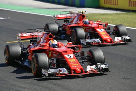German Formula One driver Sebastian Vettel of Scuderia Ferrari, left, and his first runner-up teammate Finnish Formula One driver Kimi Raikkonen of Scuderia Ferrari are seen after Vettel took the pole position during the qualifying session at Hungaroring circuit in Mogyorod, 23 kms north-east of Budapest, Hungary, Saturday, July 29, 2017. The Hungarian Formula One Grand Prix will be held on Sunday July, 30. (Zsolt Czegledi/MTI via AP)