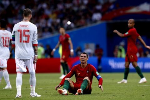 Portugal's Cristiano Ronaldo sits on the ground and look at Spain's Sergio Ramos as after the end of the the group B match between Portugal and Spain at the 2018 soccer World Cup in the Fisht Stadium in Sochi, Russia, Friday, June 15, 2018. (AP Photo/Manu Fernandez)