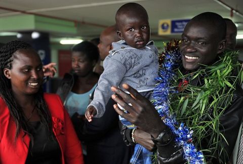 Kenya's Dennis Kimetto (R) holds his son Alvin after arriving in Nairobi on October 1, 2014, returning from Berlin where he clocked a world record of 2hr 02min 57sec to win the Berlin Marathon on September 28. Kimetto smashed the world record in the Berlin Marathon as he made history by becoming the first man to break the 2hr 03min barrier. The 30-year-old runner says he wants to set a new record next year. AFP PHOTO / TONY KARUMBA        (Photo credit should read TONY KARUMBA/AFP/Getty Images)