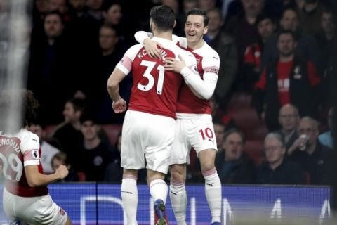 Arsenal's Mesut Ozil, right, celebrates scoring his side's first goal of the game against Bournemouth, with teammate Sead Kolasinac, centre, during their English Premier League soccer match at the Emirates Stadium in London, Wednesday Feb. 27, 2019. (Adam Davy/PA via AP)
