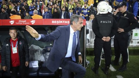 Besiktas coach Senol Gunes gestures after an object hit his head during the Turkish Cup semi-final second leg match between Besiktas and Fenerbahce in Istanbul, Thursday, April 19, 2018. The Turkish Cup semifinal between Fenerbahce and Besiktas was abandoned on Thursday after visiting coach Senol Gunes was injured by an object thrown from the stands. (AP Photo)