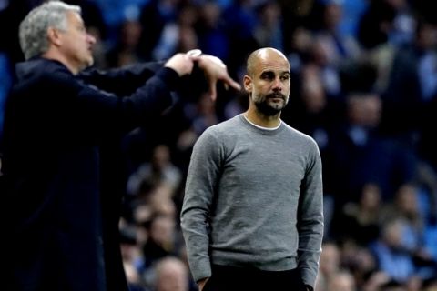 Manchester United manager Jose Mourinho gestures next to Manchester City coach Pep Guardiola, right, during the English Premier League soccer match between Manchester City and Manchester United at the Etihad Stadium in Manchester, England, Saturday April 7, 2018. (AP Photo/Matt Dunham)