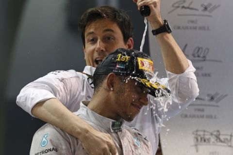 Mercedes driver Lewis Hamilton of Britain is doused as he celebrates with Mercedes team boss Toto Wolff after winning the Emirates Formula One Grand Prix to clinch the Formula One world championship at the Yas Marina racetrack in Abu Dhabi, United Arab Emirates, Sunday, Nov. 23, 2014. (AP Photo/Luca Bruno)