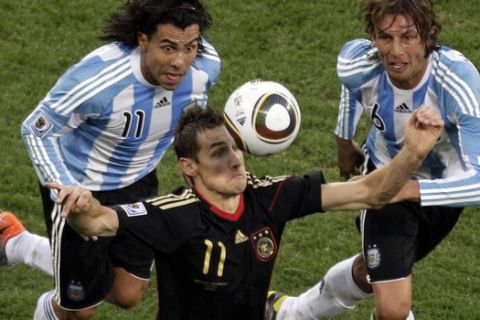Germany's Miroslav Klose, center, goes for the ball as Argentina's Carlos Tevez, left, and Gabriel Heinze, right, follow him, during the World Cup quarterfinal soccer match between Argentina and Germany at the Green Point stadium in Cape Town, South Africa, Saturday, July 3, 2010. Germany won 4-0. (AP Photo/Michael Sohn)