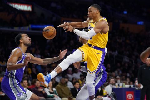 Los Angeles Lakers guard Russell Westbrook, right, passes the ball as Sacramento Kings forward Trey Lyles defends during the first half of a preseason NBA basketball game Monday, Oct. 3, 2022, in Los Angeles. (AP Photo/Mark J. Terrill)