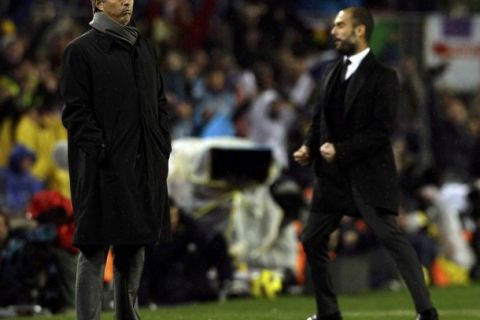 Barcelona's coach Pep Guardiola (R) and Real Madrid's coach Jose Mourinho react after Barcelona's second goal during their Spanish first division soccer match at Nou Camp stadium in Barcelona, November 29, 2010.   REUTERS/Albert Gea (SPAIN  - Tags: SPORT SOCCER)  