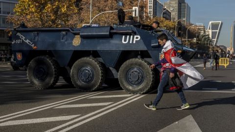 A River Plate supporter walks past an Armored Personnel Carrier ahead of the Copa Libertadores Final between River Plate and Boca Juniors in Madrid, Sunday, Dec. 9, 2018. Tens of thousands of Boca and River fans are in the city for the "superclasico" at Santiago Bernabeu Stadium on Sunday. (AP Photo/Olmo Calvo)