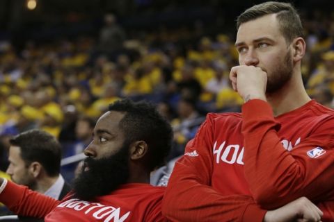 Houston Rockets' James Harden, left, and Donatas Motiejunas watch from the bench in the closing seconds in Game 5 of a first-round NBA basketball playoff series against the Golden State Warriors on Wednesday, April 27, 2016, in Oakland, Calif. Golden State won 114-81. (AP Photo/Marcio Jose Sanchez)