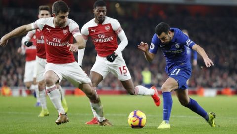 Chelsea's Pedro, right falls as he vies for the ball with Arsenal's Sokratis Papastathopoulos during the English Premier League soccer match between Arsenal and Chelsea at the Emirates stadium in London, Saturday, Jan. 19, 2019. (AP Photo/Frank Augstein)