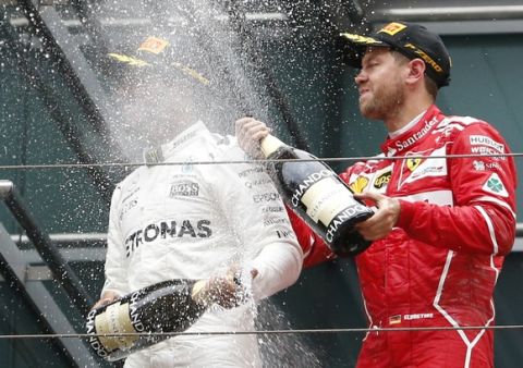 Mercedes driver Lewis Hamilton, left, of Britain is sprayed with champagne by Ferrari driver Sebastian Vettel of Germany on the podium after winning the Chinese Formula One Grand Prix at the Shanghai International Circuit in Shanghai, China, Sunday, April 9, 2017. Vettel finished second. (AP Photo/Toru Takahashi)