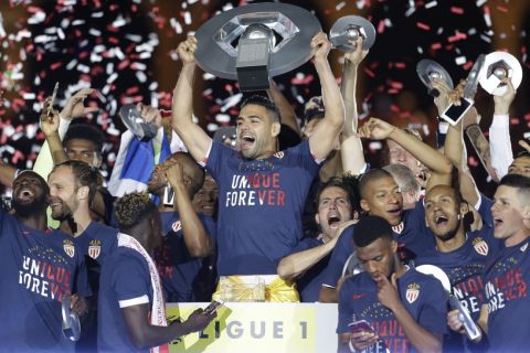 Monaco players hold the trophy as they celebrate their French League One title after beating Saint Etienne during the League One soccer match Monaco against Saint Etienne, at the Louis II stadium in Monaco, Wednesday, May 17, 2017. Monaco clinched its first league title since 2000 and eighth overall, replacing Paris Saint-Germain as champion. (AP Photo/Claude Paris)