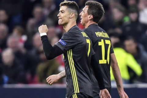 Juventus' Cristiano Ronaldo, left, celebrates after scoring his side's opening goal during the Champions League quarterfinal, first leg, soccer match between Ajax and Juventus at the Johan Cruyff ArenA in Amsterdam, Netherlands, Wednesday, April 10, 2019. (AP Photo/Martin Meissner)