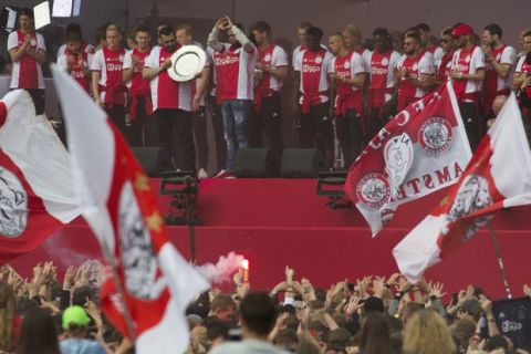 The father of former Ajax soccer player Abdelhak Nouri holds the trophy as players and fans celebrate clinching Ajax's 34th Dutch Premier League soccer title in Amsterdam, Netherlands, Thursday, May 16, 2019. In 2017 Nouri, who played with number 34, collapsed and suffered a cardiac attack, which left him with severe and permanent brain damage. (AP Photo/Peter Dejong)
