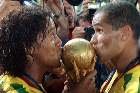 ** FOR USE AS DESIRED, PHOTOS OF THE DECADE ** FILE - Brazil's Ronaldinho, left, and Rivaldo kiss the World Cup trophy during a victory lap after the 2002 World Cup final soccer match between Brazil and Germany, in this June 30, 2002 file photo, in Yokohama, Japan. Brazil won the match 2-0. (AP Photo/Luca Bruno, File)