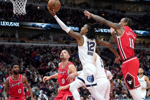 Memphis Grizzlies' Ja Morant (12) scores past Chicago Bulls' DeMar DeRozan during the second half of an NBA basketball game Saturday, Feb. 26, 2022, in Chicago. (AP Photo/Charles Rex Arbogast)
