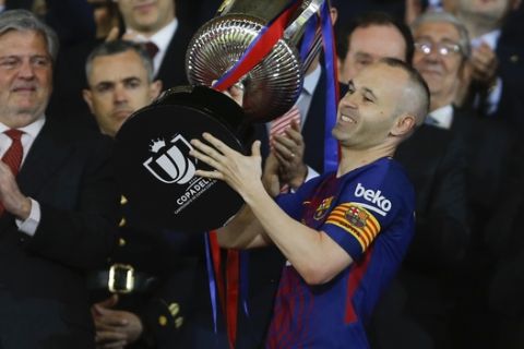 FC Barcelona's Andres Iniesta holds up the trophy as he celebrates during an award ceremony after defeating Sevilla 5-0 in the Copa del Rey final soccer match at the Wanda Metropolitano stadium in Madrid, Spain, Saturday, April 21, 2018. (AP Photo/Francisco Seco)
