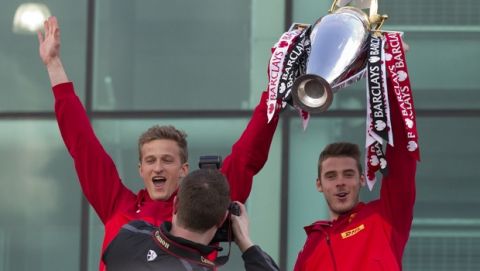 Manchester United's David De Gea, right, and fellow goalkeeper Anders Lindegaard hold the trophy outside Old Trafford Stadium as the team prepare to parade across Manchester after winning the English Premier League, Manchester, England, Monday May 13, 2013. Manager Alex Ferguson will retire at the end of the season after more than 26 years in charge at the club. (AP Photo/Jon Super)