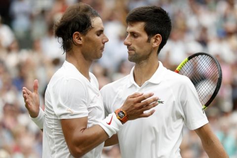 Novak Djokovic of Serbia, right, meets Rafael Nadal of Spain at the net after defeating him in the men's singles semifinal match at the Wimbledon Tennis Championships, in London, Saturday July 14, 2018. (Nic Bothma, Pool via AP)