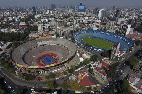 The Plaza de Toros Mexico bullring, left, that has been transformed to host an upcoming exhibition tennis match between Swiss great Roger Federer and German rival Alexander Zverev, sits next to the Estadio Azul soccer stadium, in Mexico City, Friday, Nov. 22, 2019. For 73 years, Plaza de Toros Mexico has been witness to mostly great bullfights and mighty matadors, but it as also hosted motocross events, concerts, as well as wrestling and boxing matches. (AP Photo/Rebecca Blackwell)