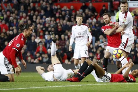 Manchester United's Zlatan Ibrahimovic, left, after attempting an overhead kick, as team-mate Marcus Rashford and Burnley's Phil Bardsley get caught up in the aftermath during the English Premier League soccer match at Old Trafford, Manchester, England, Tuesday, Dec. 26, 2017. (Martin Rickett/PA via AP)