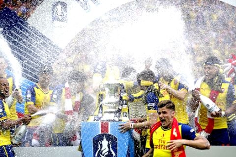 Arsenal's Theo Walcott, left, sprays champagne as he celebrates after the English FA Cup final soccer match between Aston Villa and Arsenal at Wembley stadium in London, Saturday, May  30, 2015. Arsenal won the match 4-0. (AP Photo/Alastair Grant) 